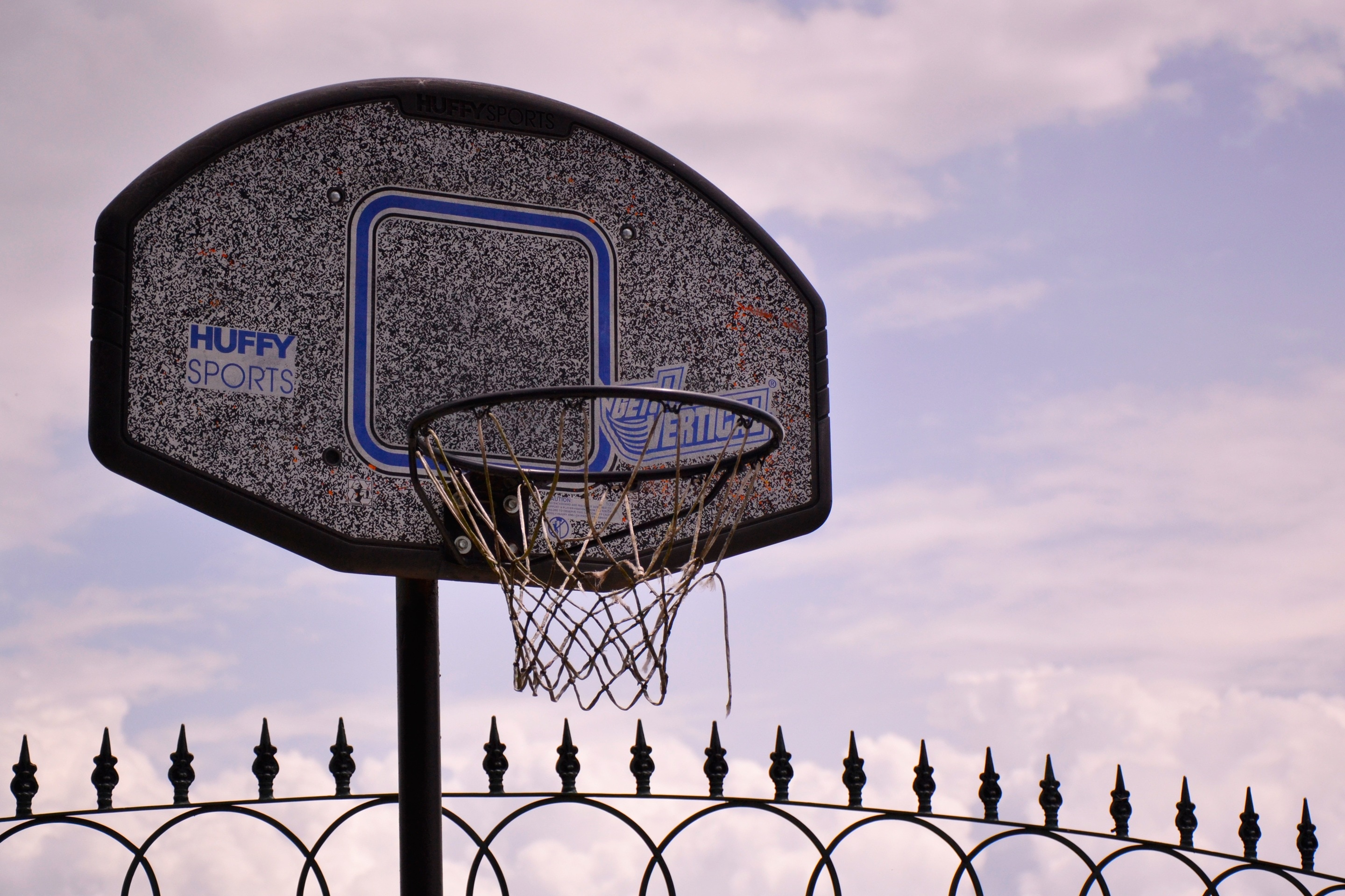 grey and blue basketball system near black metal fence'