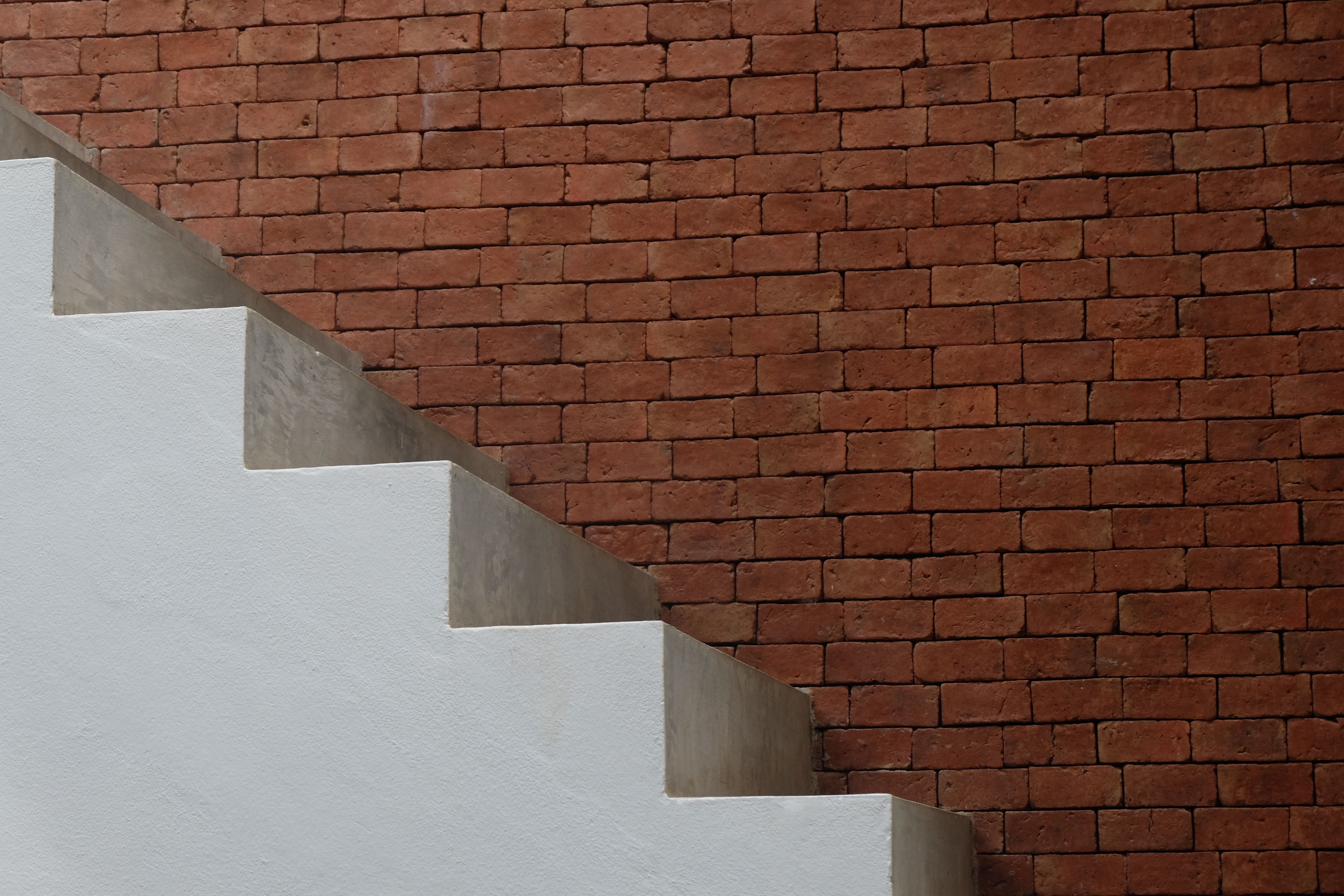 white concrete stairs and brown bricked wall