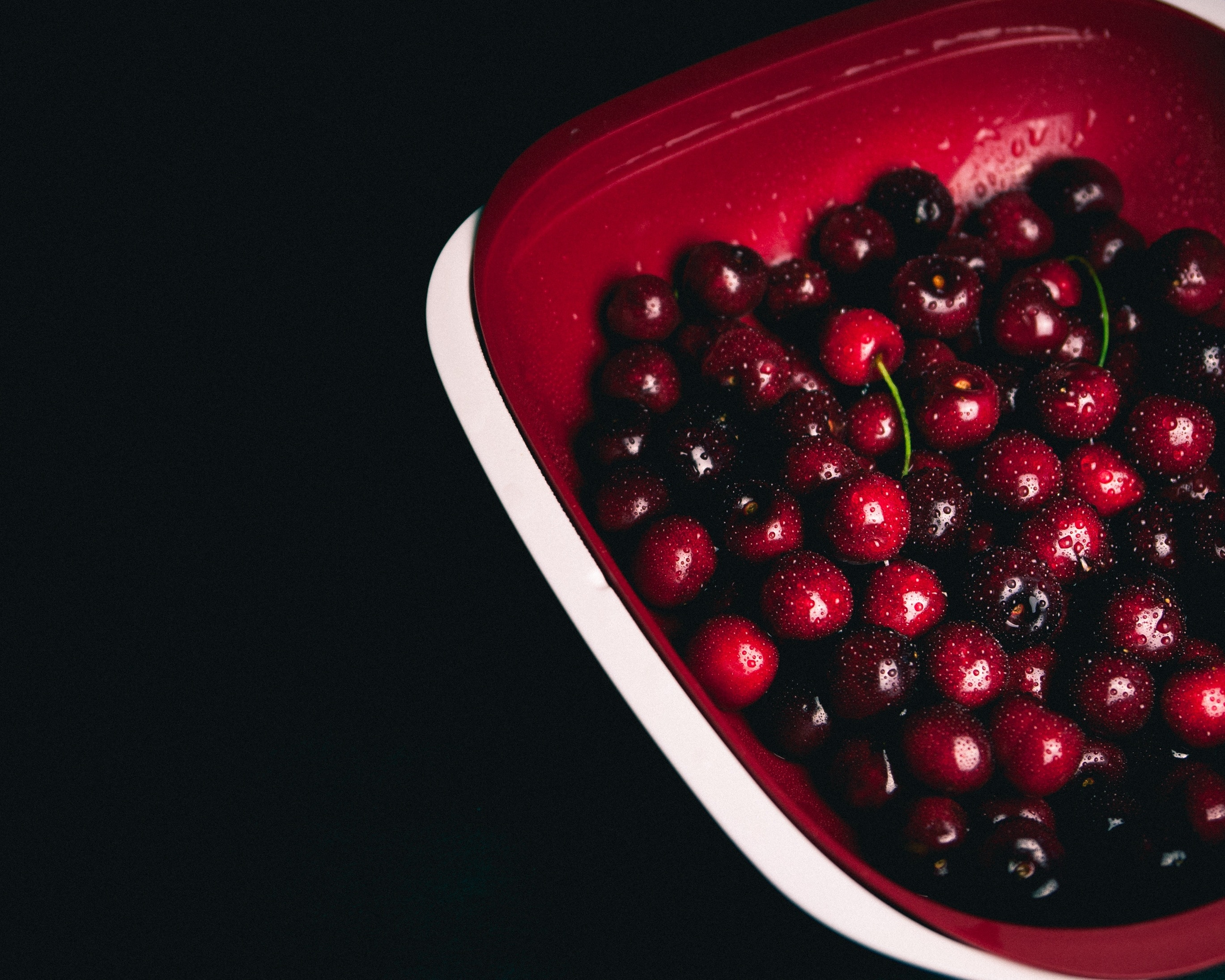 cherries  on red plastic bowl
