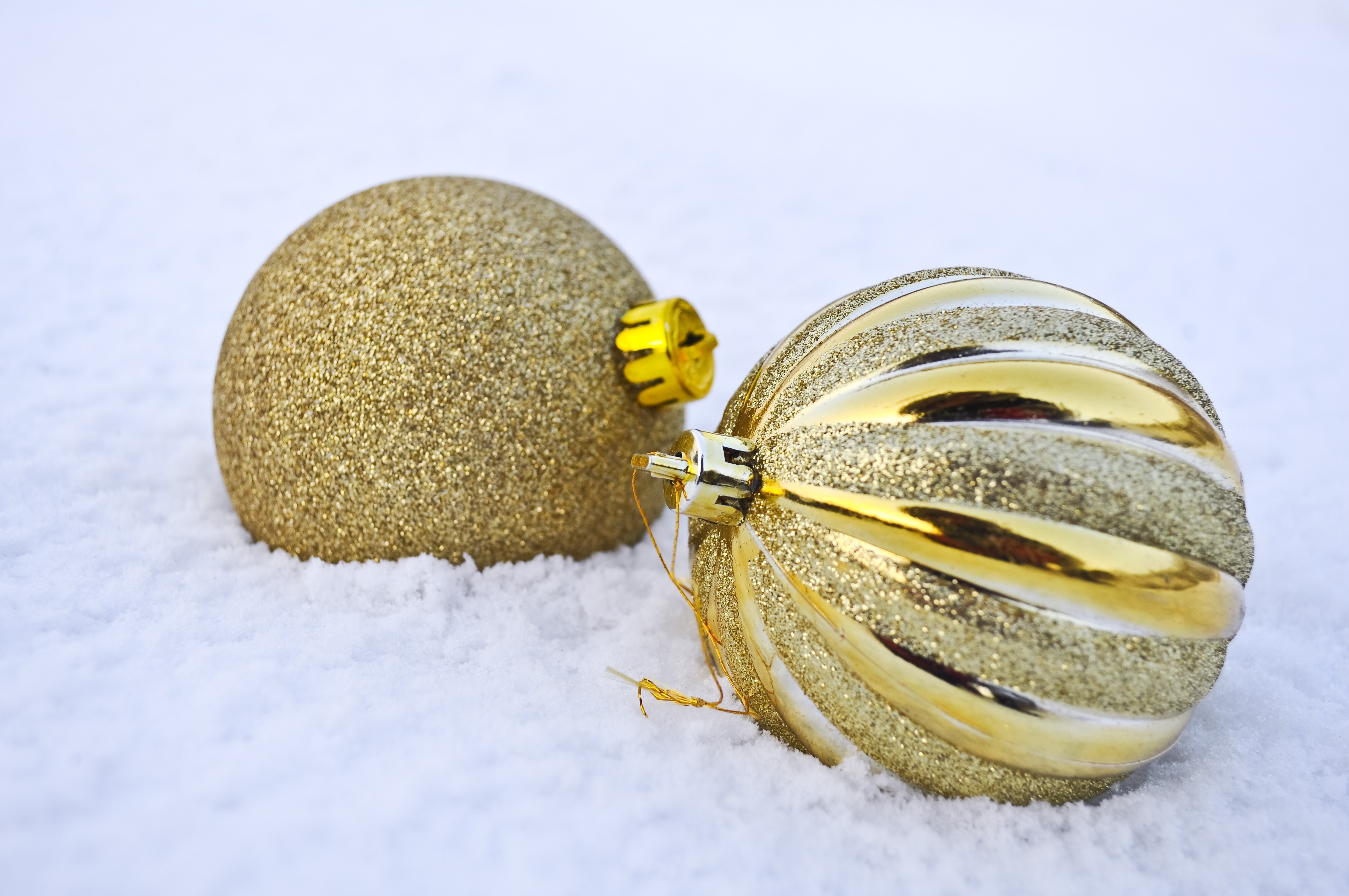 two gold christmas balls on snow