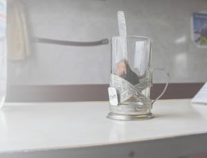 clear glass cup with silver spoon on white surface thumbnail