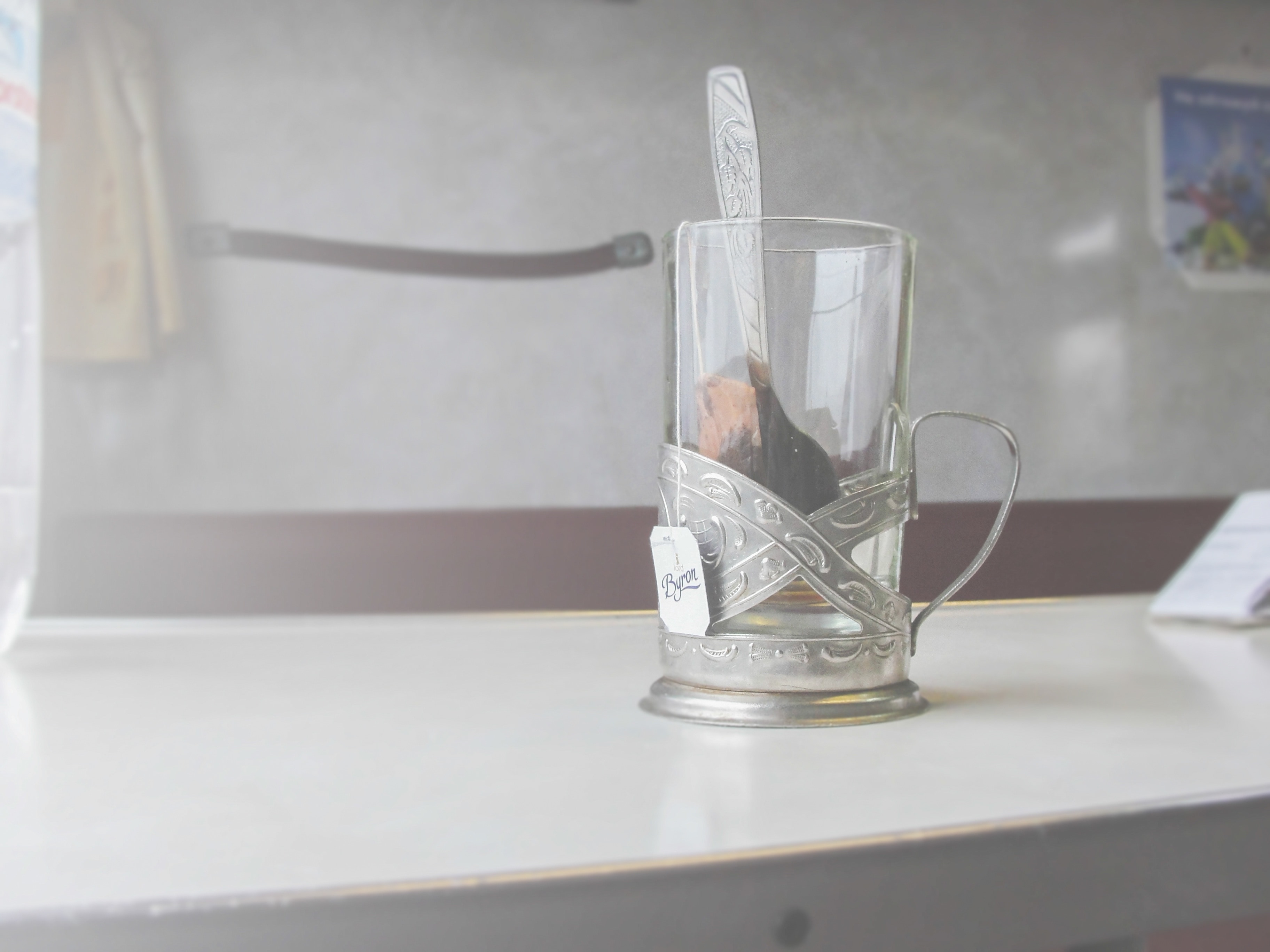clear glass cup with silver spoon on white surface