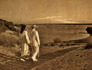 man and woman walking near seashore thumbnail