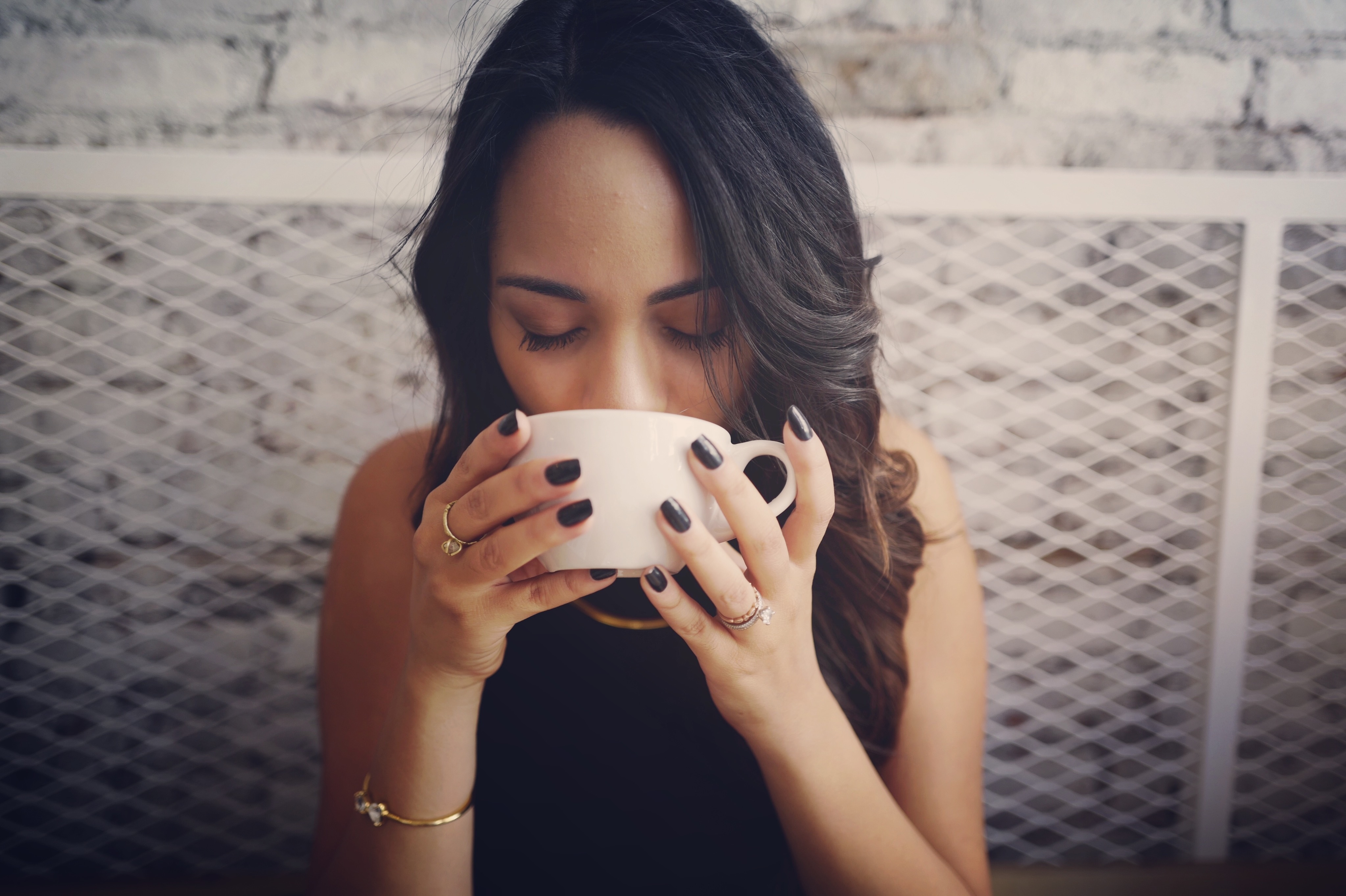 woman in black top sipping from ceramic teacup