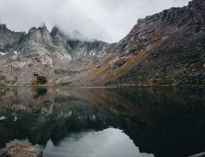 mountain beside body of water during daytime thumbnail