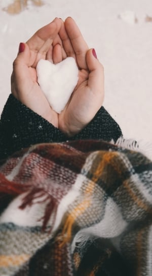 person in brown, white and black jacket holding white heart formed object thumbnail
