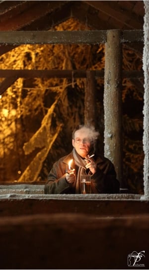 man in brown coat smoking cigar under the brown wooden shelter thumbnail