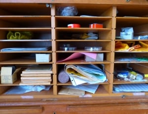 papers, boxes, and boards in brown wooden shelf thumbnail