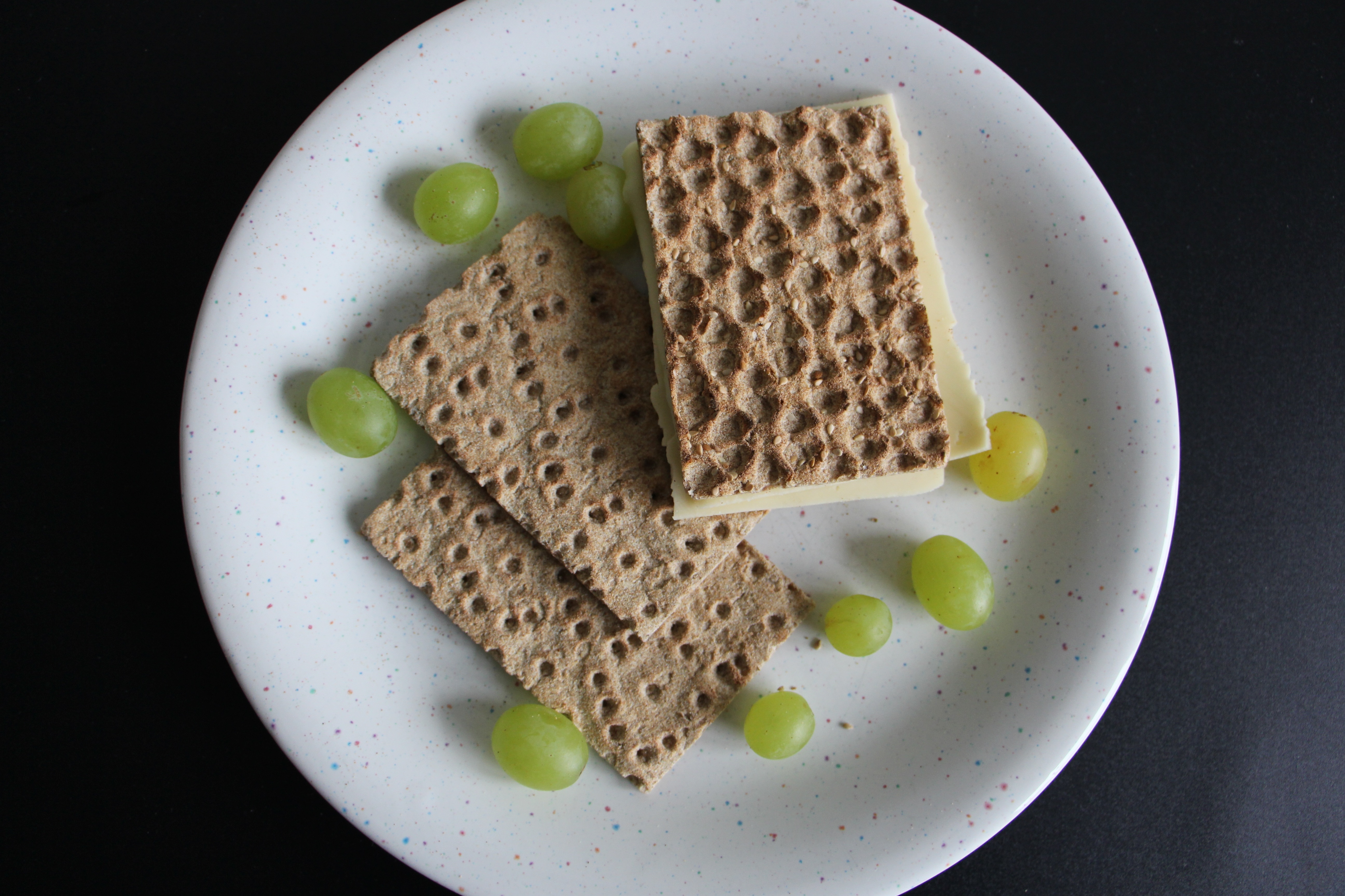 three white wafers and green grapes on white plate