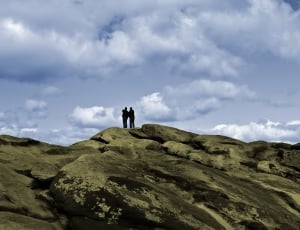 silhouette of two person on brown hills thumbnail