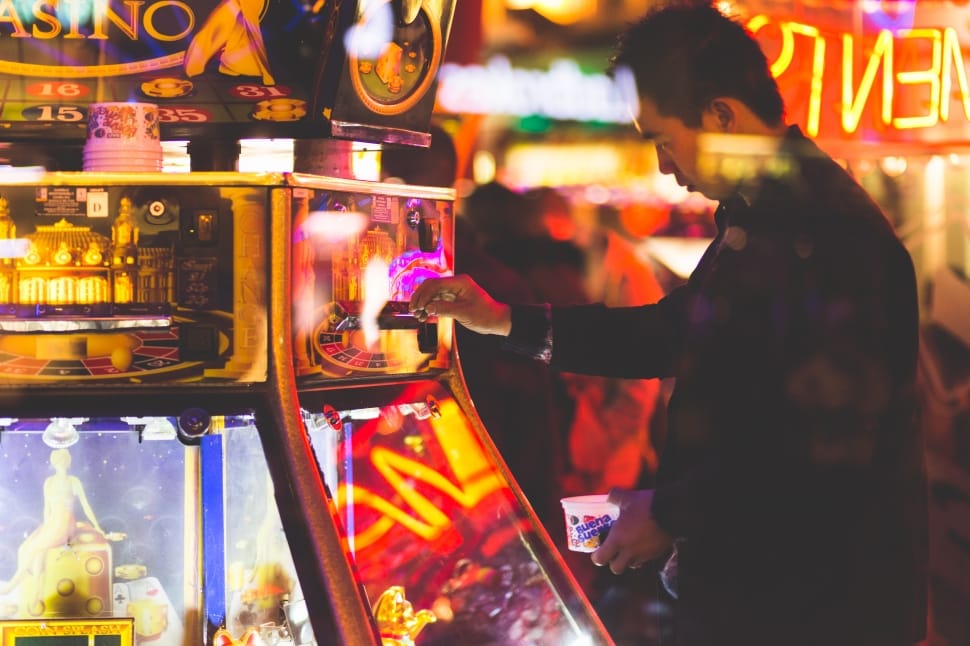 man inserting coin on arcade machine free image - Peakpx