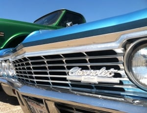 Chevrolet car beside green pickup truck under blue clear sky thumbnail