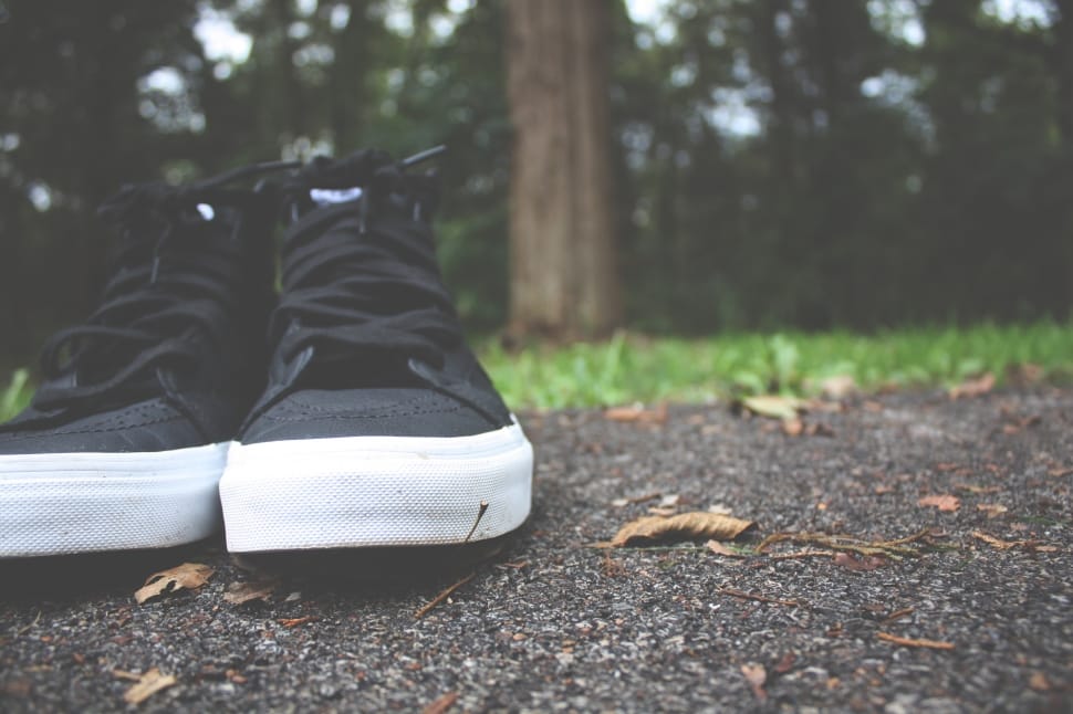 pair of black sneakers on black concrete road preview