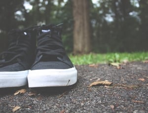 pair of black sneakers on black concrete road thumbnail