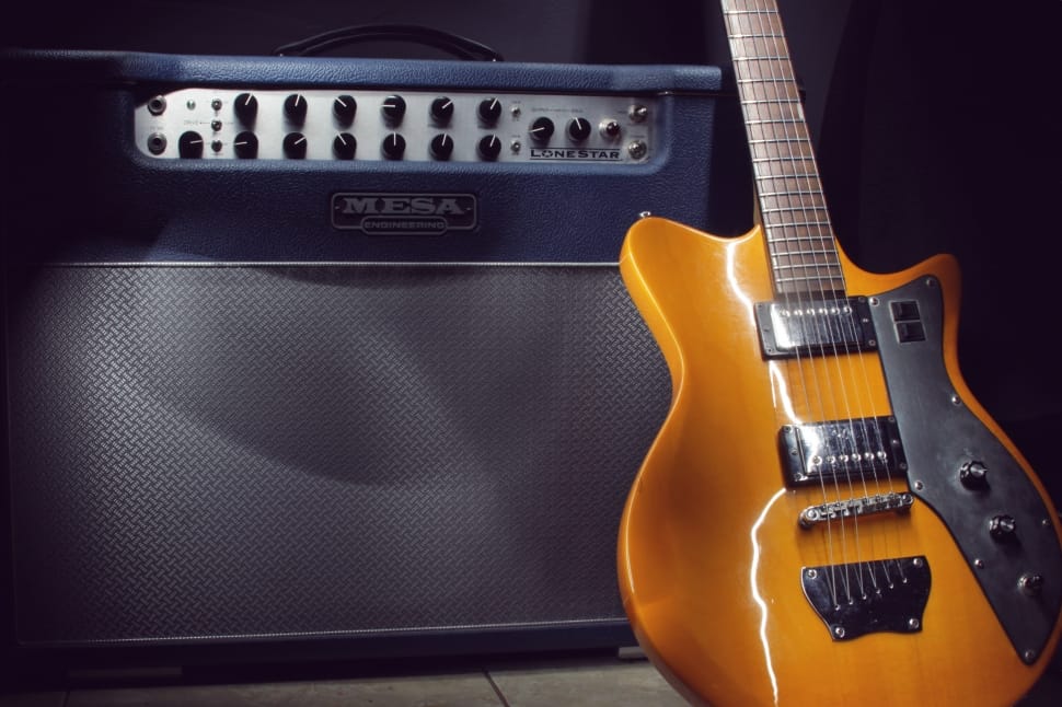 orange electric guitar near gray mena guitar amplifier preview