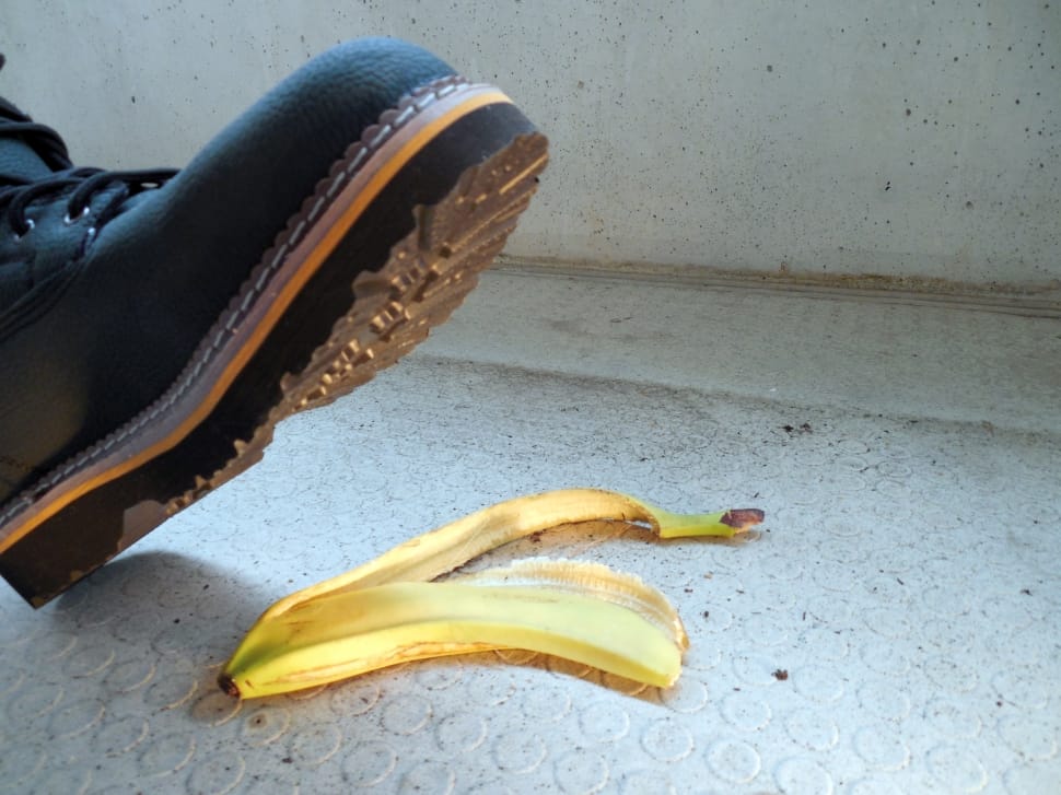person in black shoes stepping on yellow banana peel preview