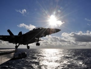 silhouette photography of a fighter jet over the body of water thumbnail