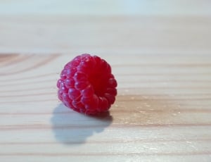red raspberry on brown wooden surface thumbnail