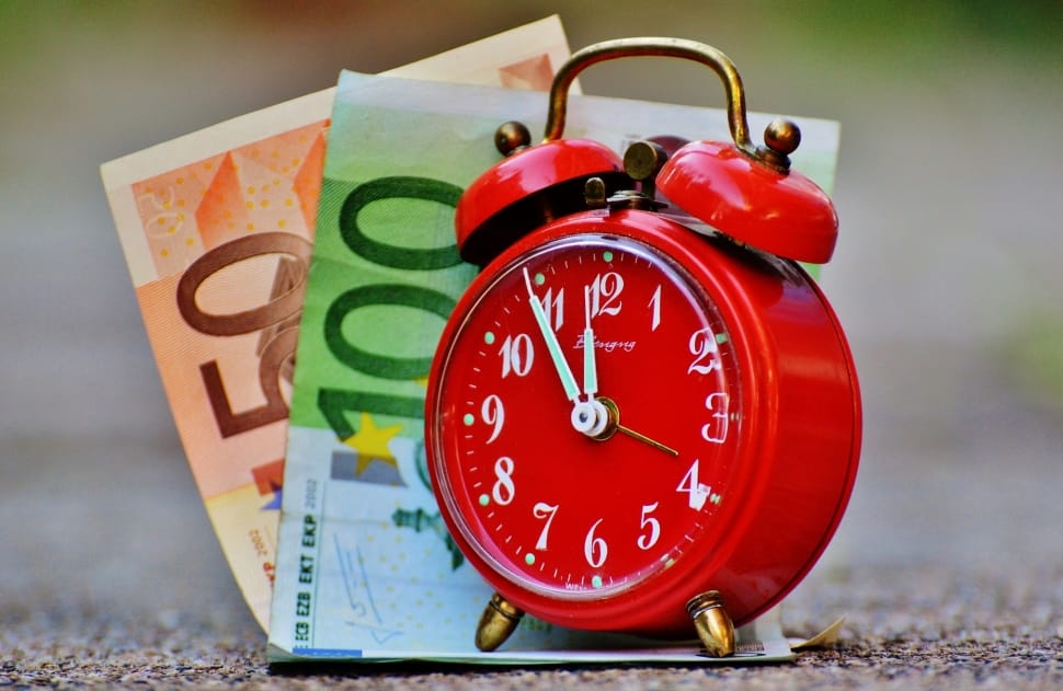 red alarm clock with 50 and 100 banknotes preview