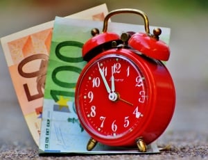 red alarm clock with 50 and 100 banknotes thumbnail