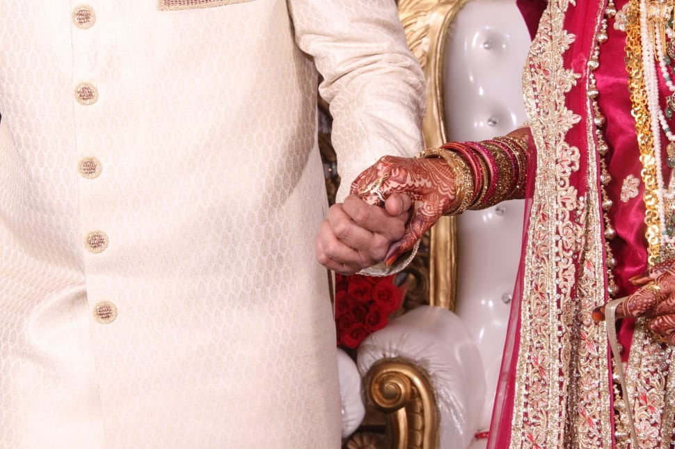 man in white sherwani holding woman in red sari preview