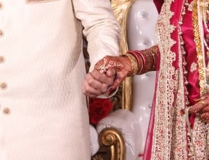 man in white sherwani holding woman in red sari thumbnail