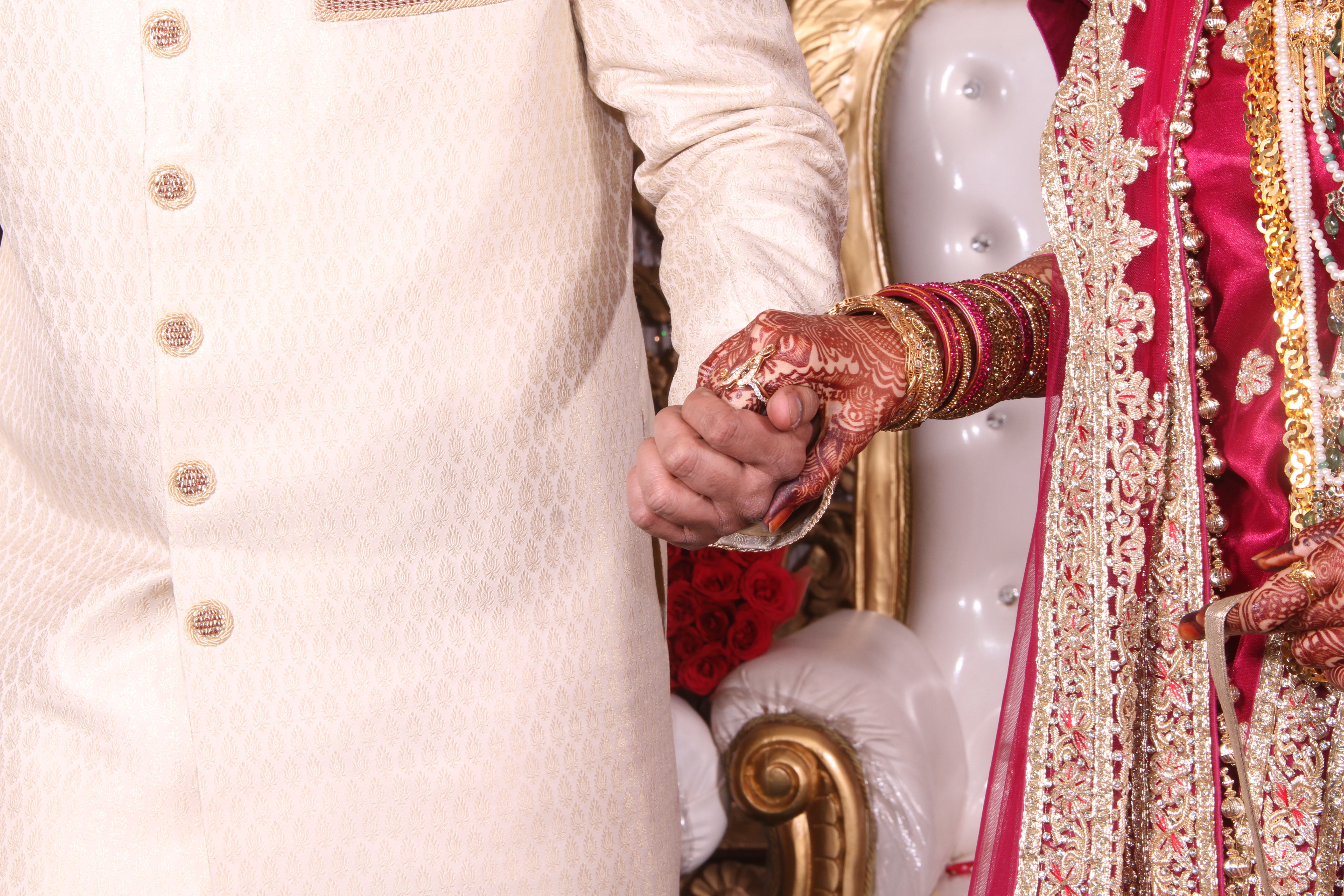 man in white sherwani holding woman in red sari