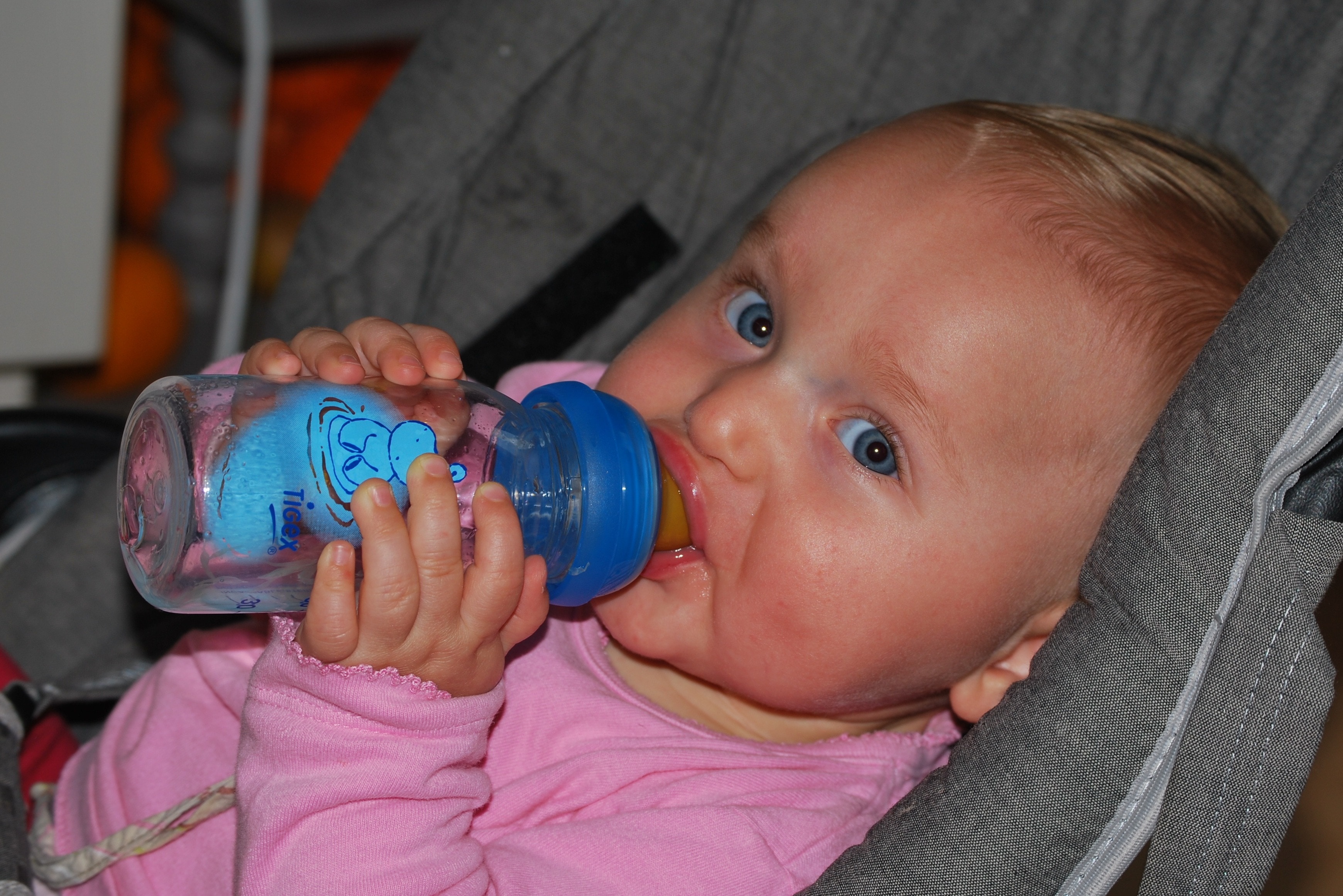 baby holding clear glass fedding bottle