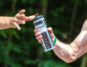 shallow focus photography of man giving black and white plastic sports bottle to other man during daytime thumbnail