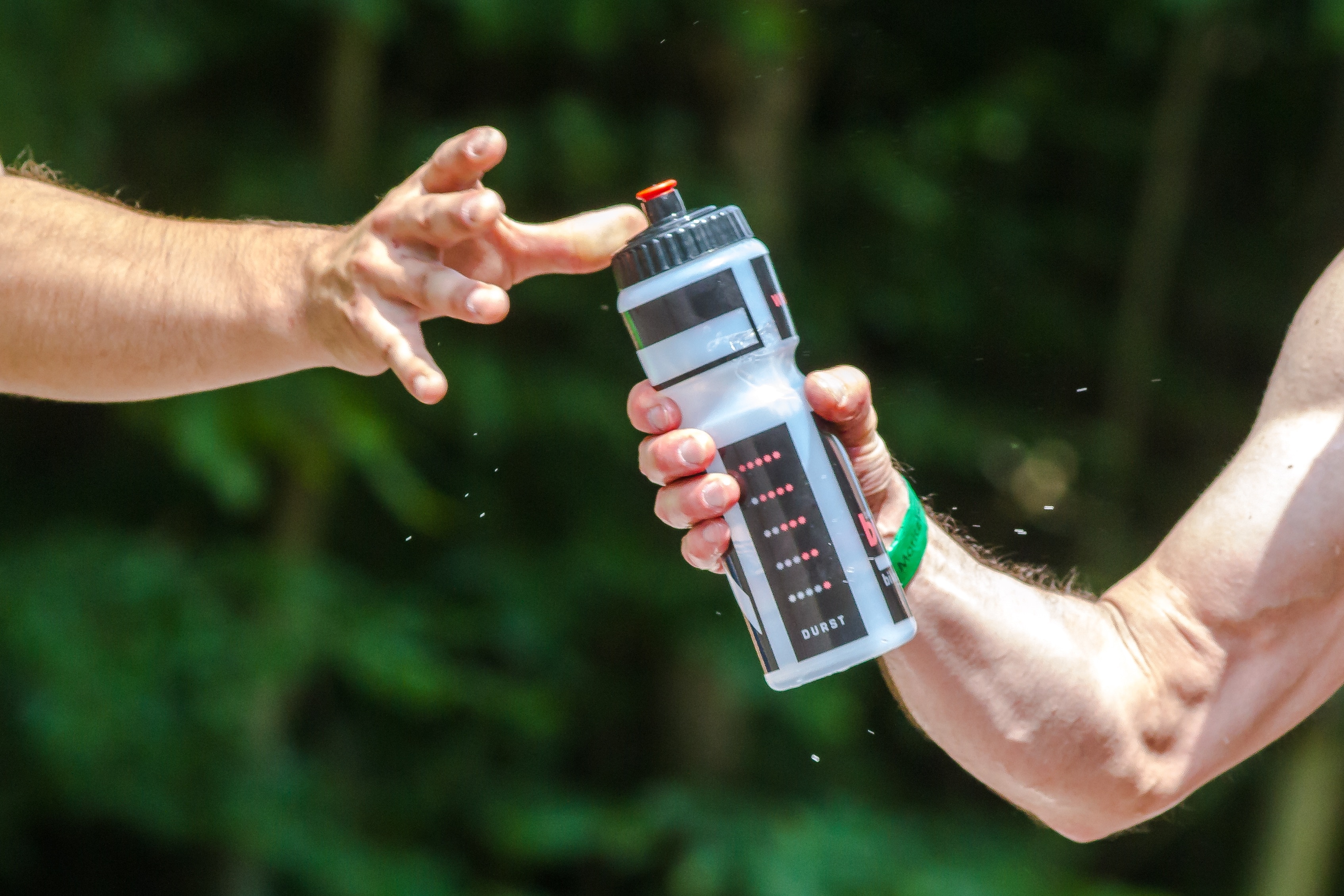 shallow focus photography of man giving black and white plastic sports bottle to other man during daytime