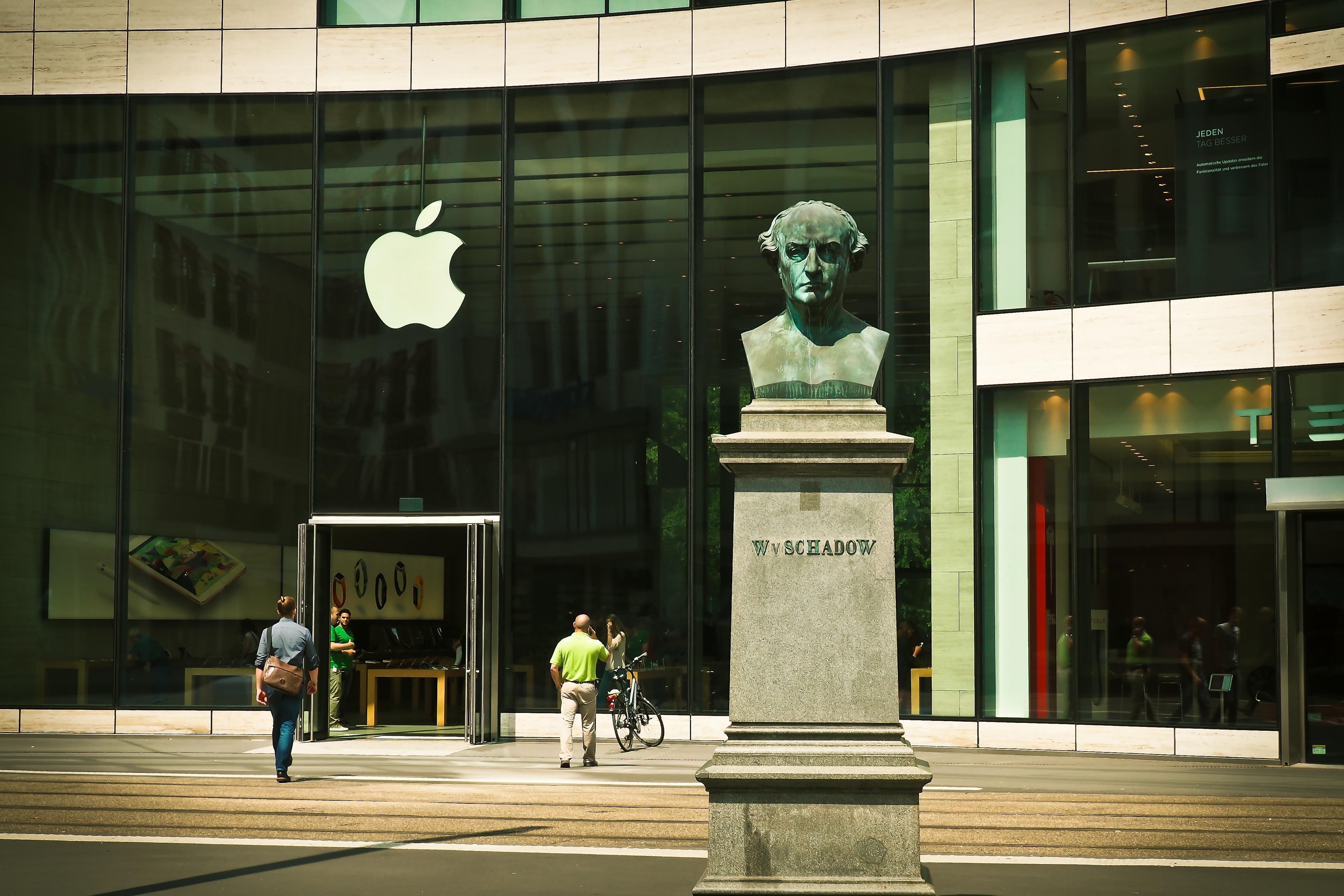 photo of man's head bust concrete statue near Apple Building during daytime