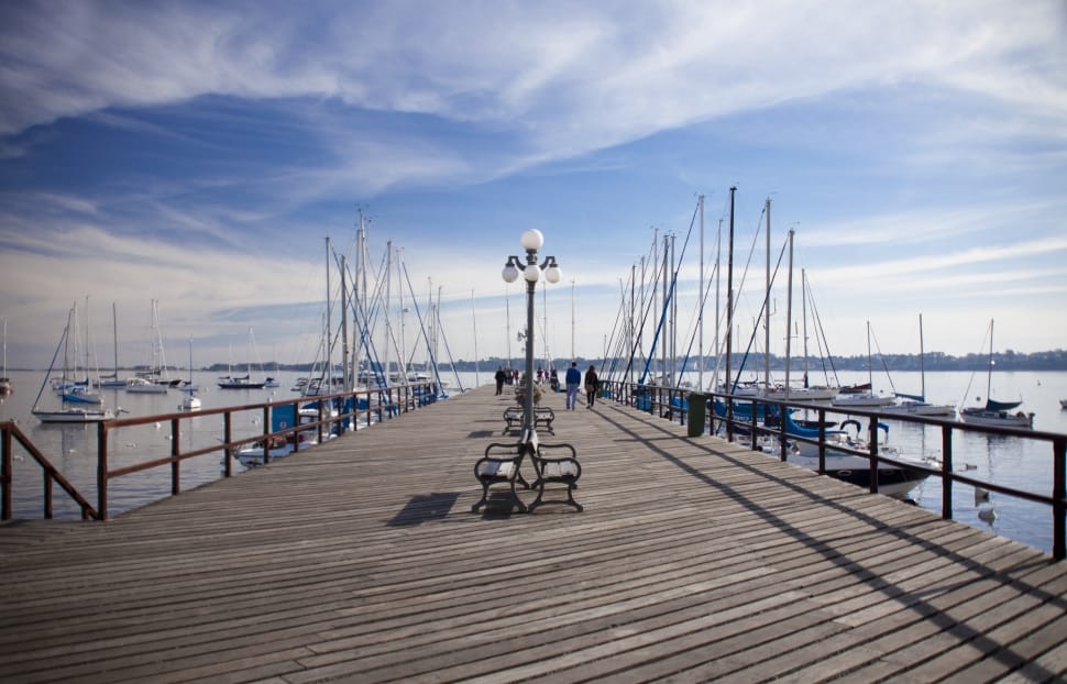 brown wooden dock and white sailboats with black lamp post and bench preview