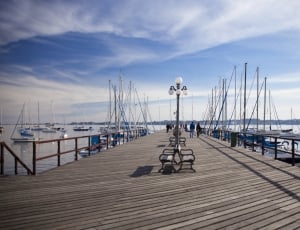brown wooden dock and white sailboats with black lamp post and bench thumbnail