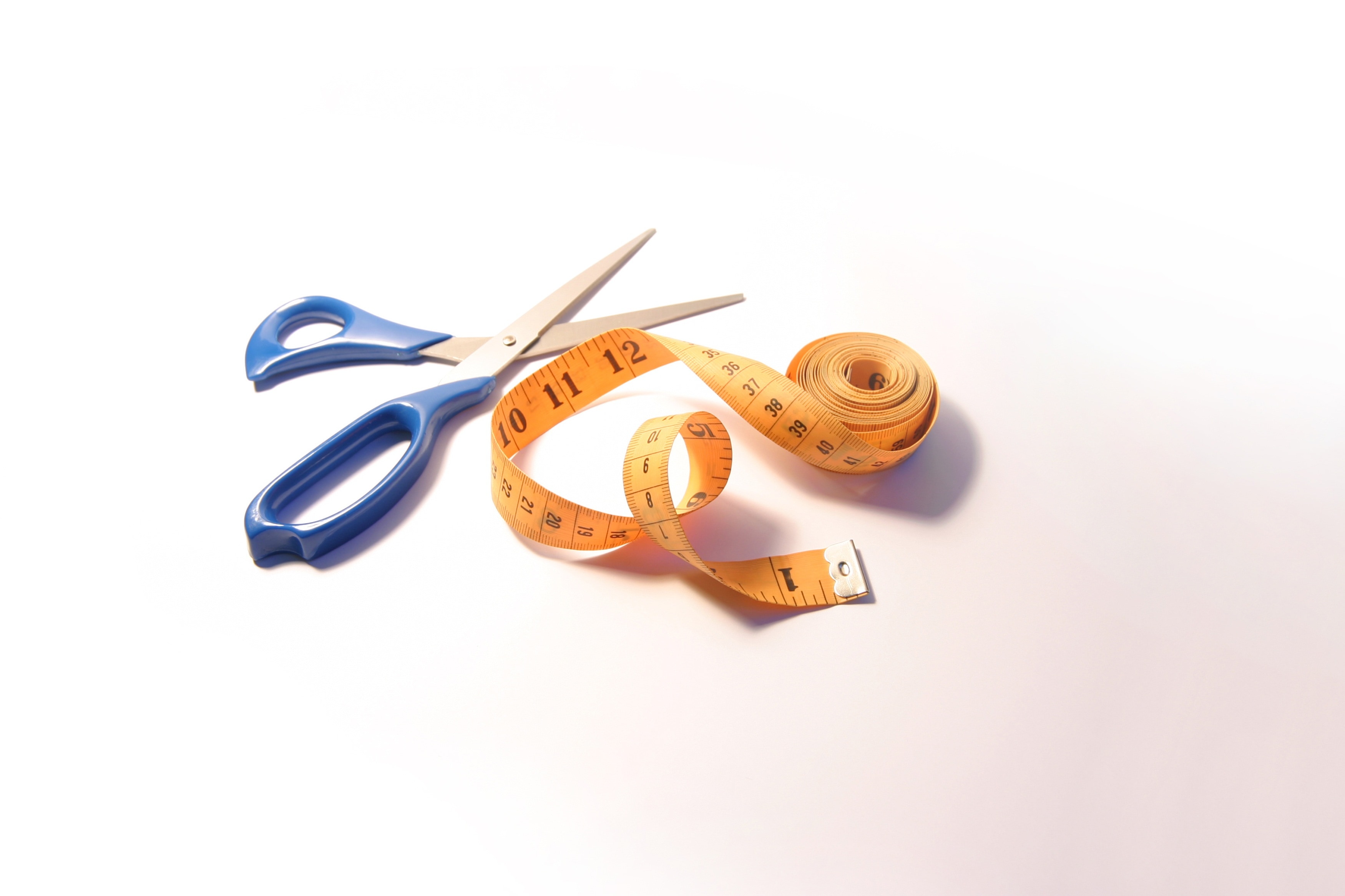 yellow tape measure beside a blue handled scissor
