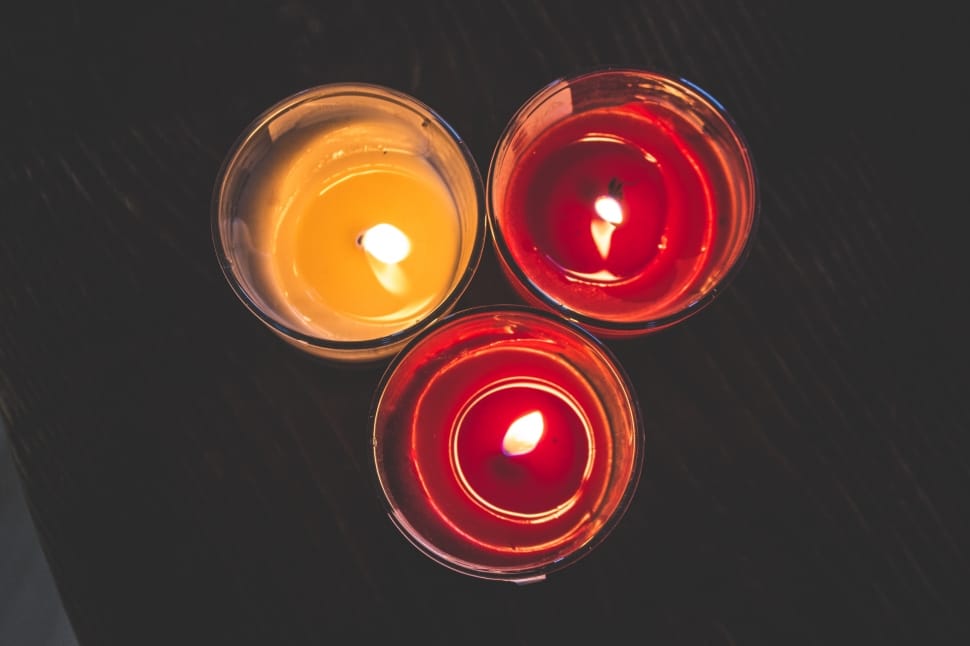 three lighted candle in glass holders on top of a black wooden surface preview