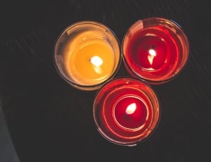 three lighted candle in glass holders on top of a black wooden surface thumbnail