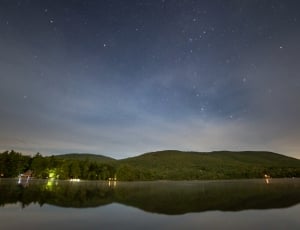 green mountains beside body of water during twilight thumbnail