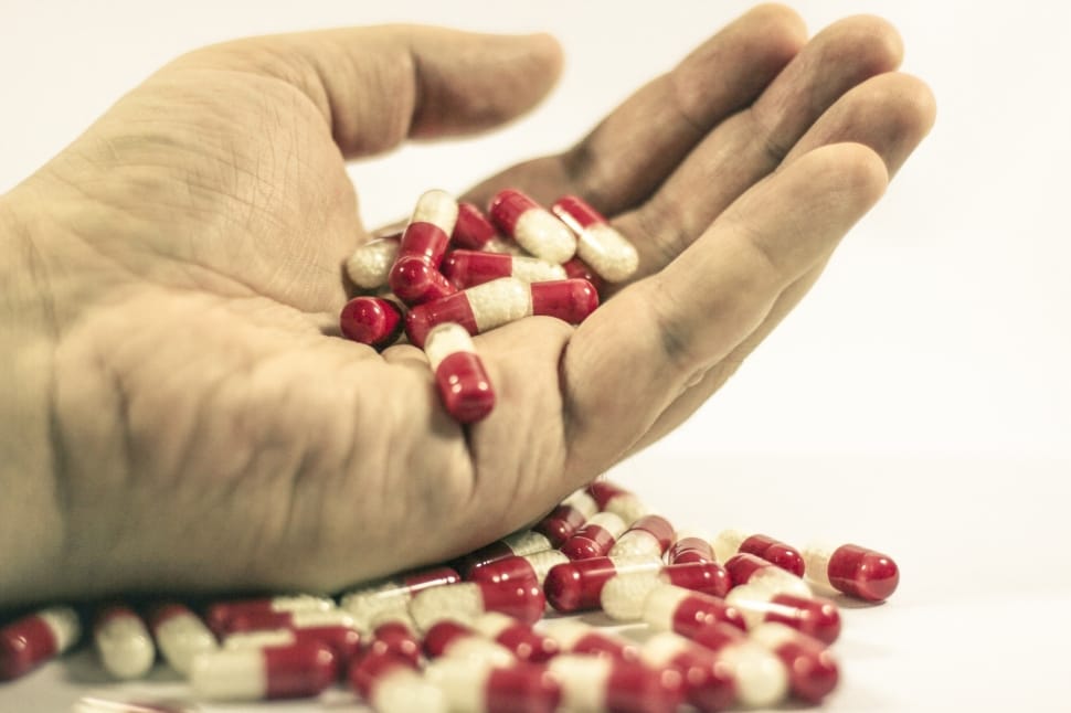 white and red medication capsules on person's hand preview