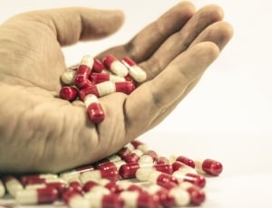 white and red medication capsules on person's hand thumbnail