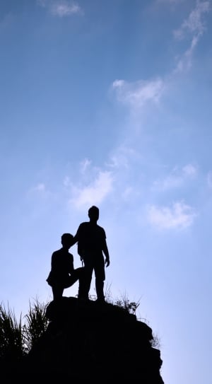 silhouette of 2 man on top of rock thumbnail