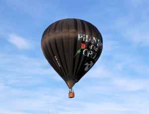 black hot air balloon under white cloudy blue sky thumbnail