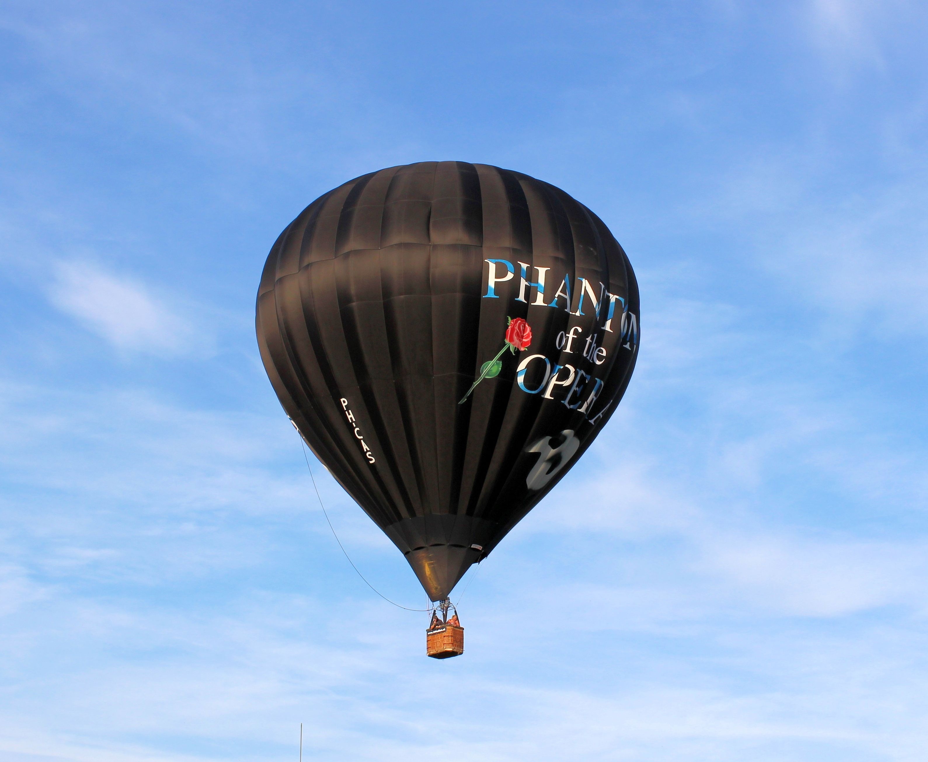 black hot air balloon under white cloudy blue sky
