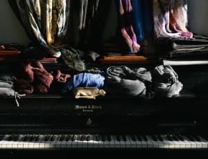assorted clothes over wooden upright piano thumbnail