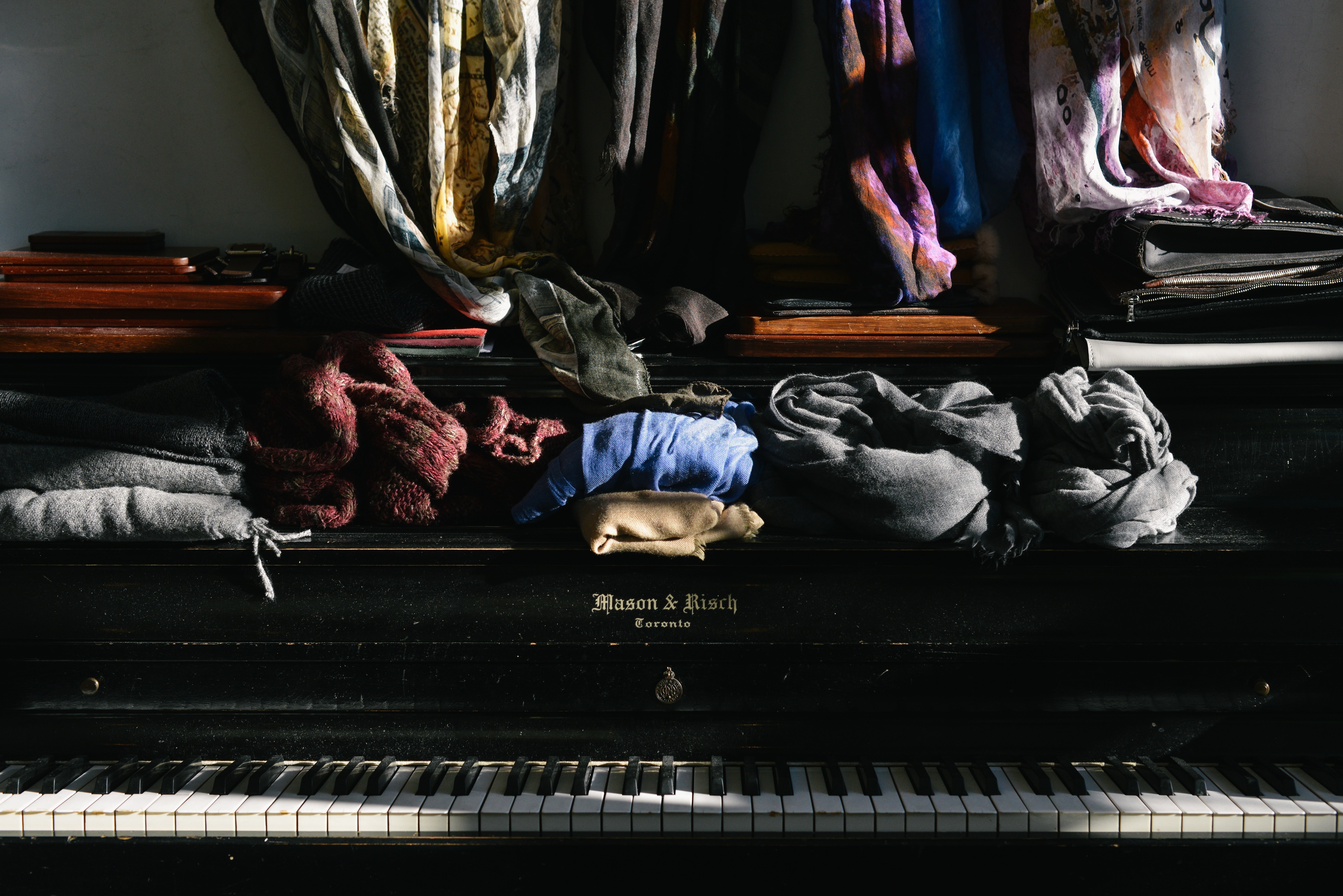 assorted clothes over wooden upright piano