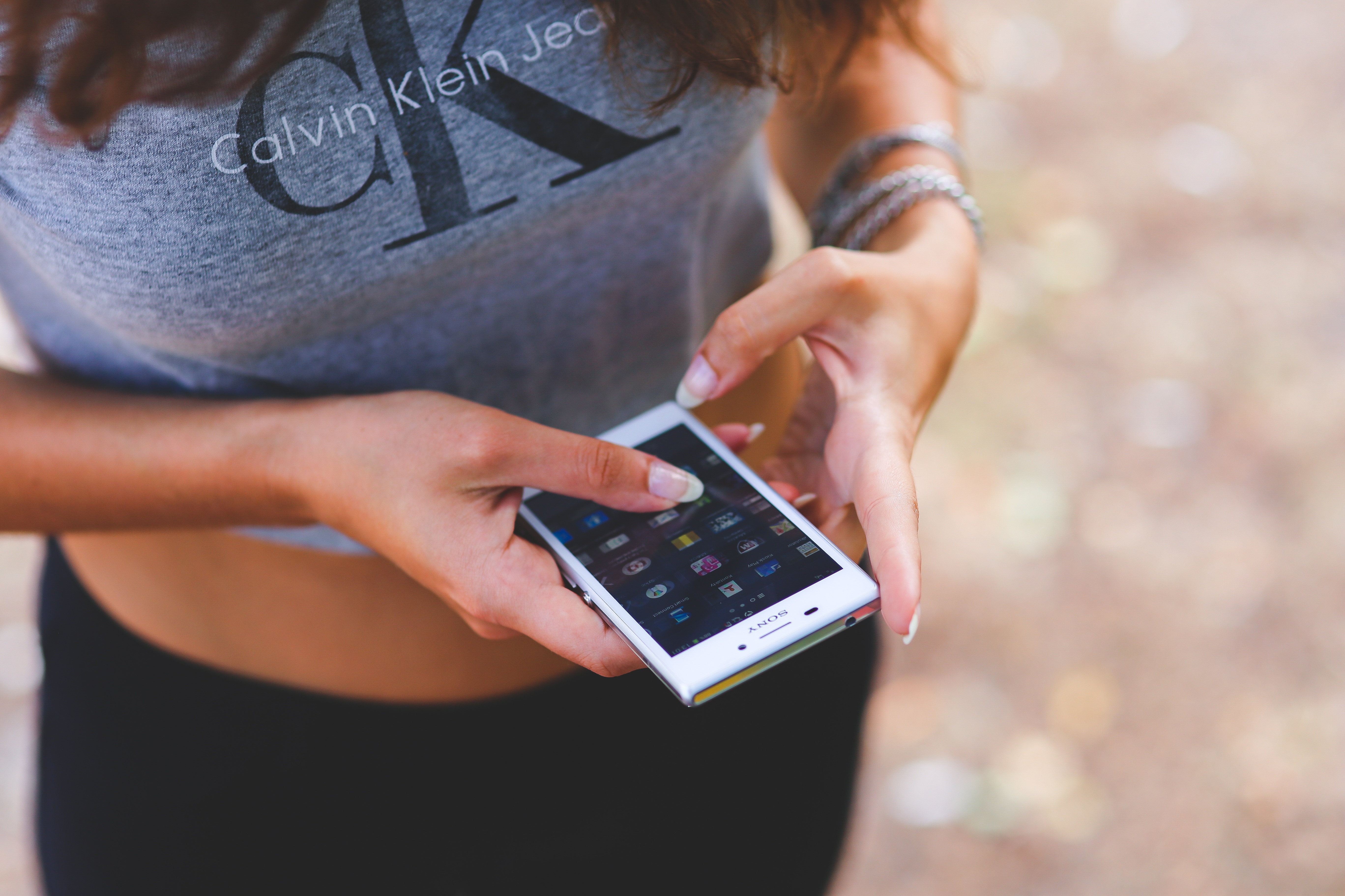 woman wearing gray calvin klein crop top holding white android smartphone
