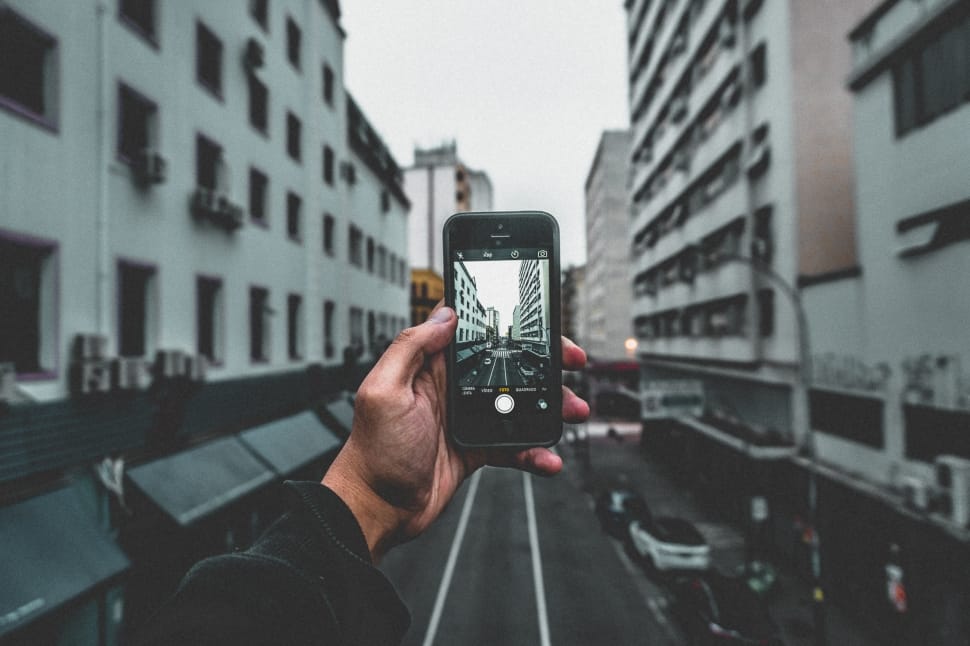 person holding black smartphone taking photo of city buildings during daytime preview