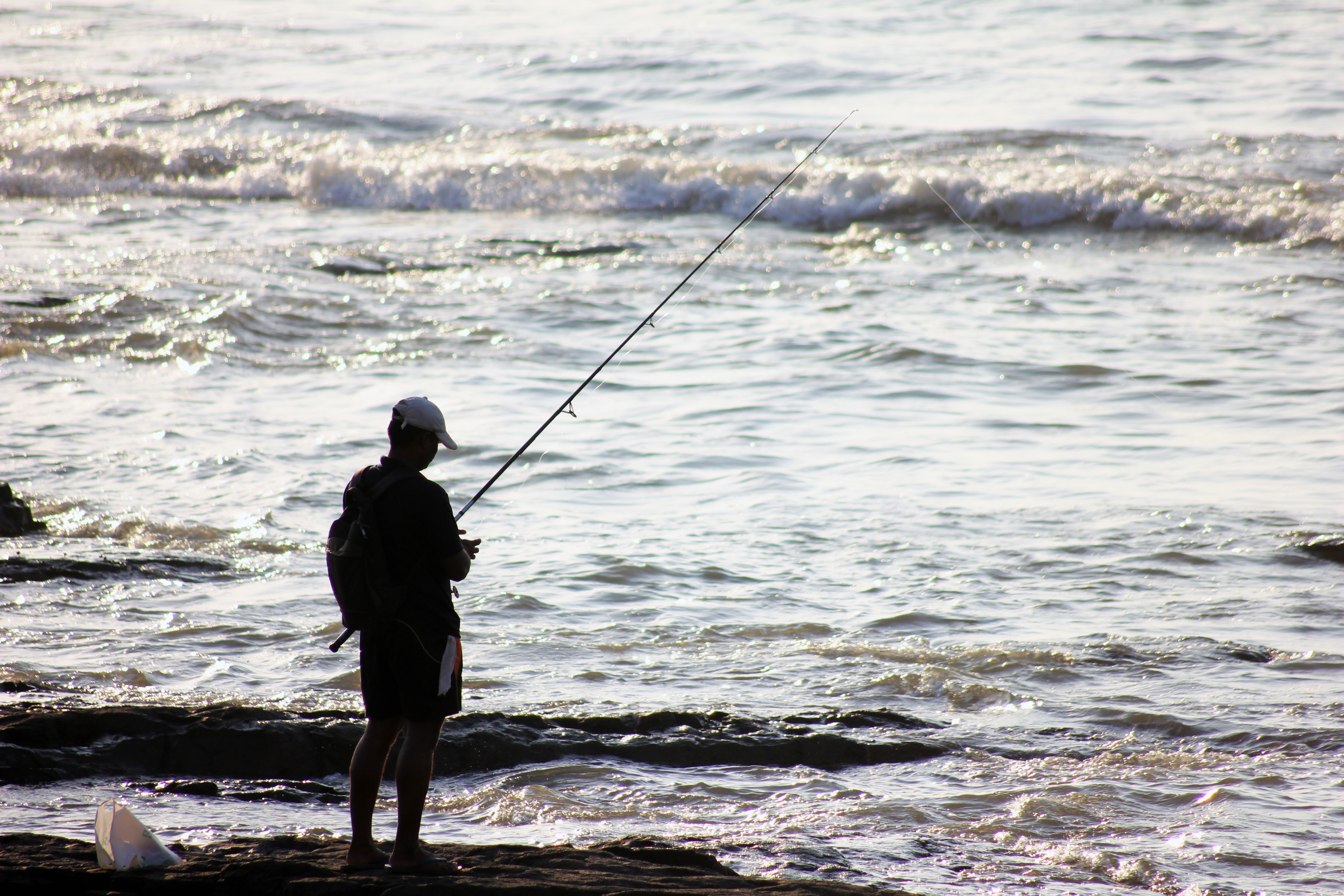 man fishing by the seashore photo