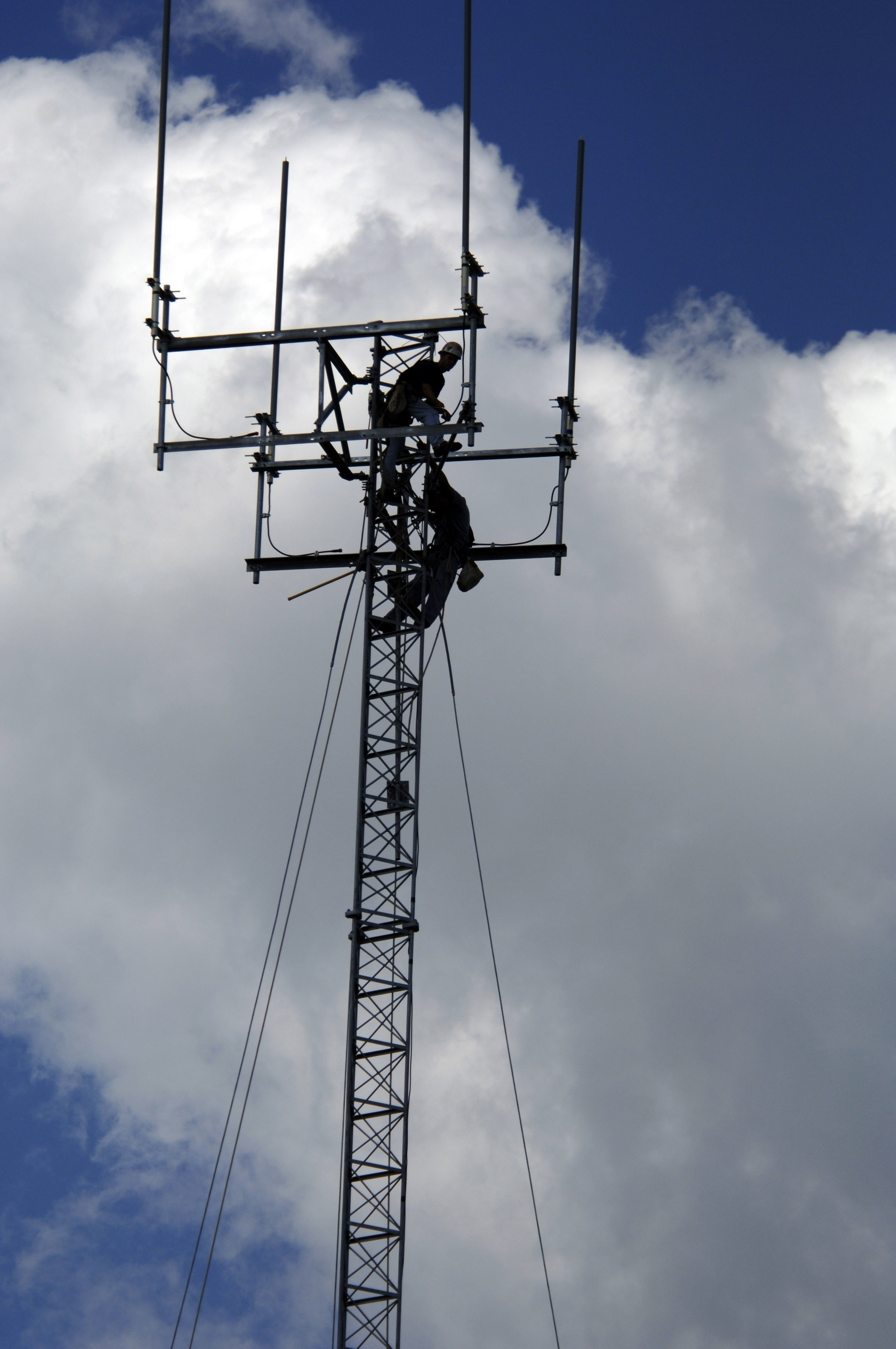 photo of man at the top of electricity tower