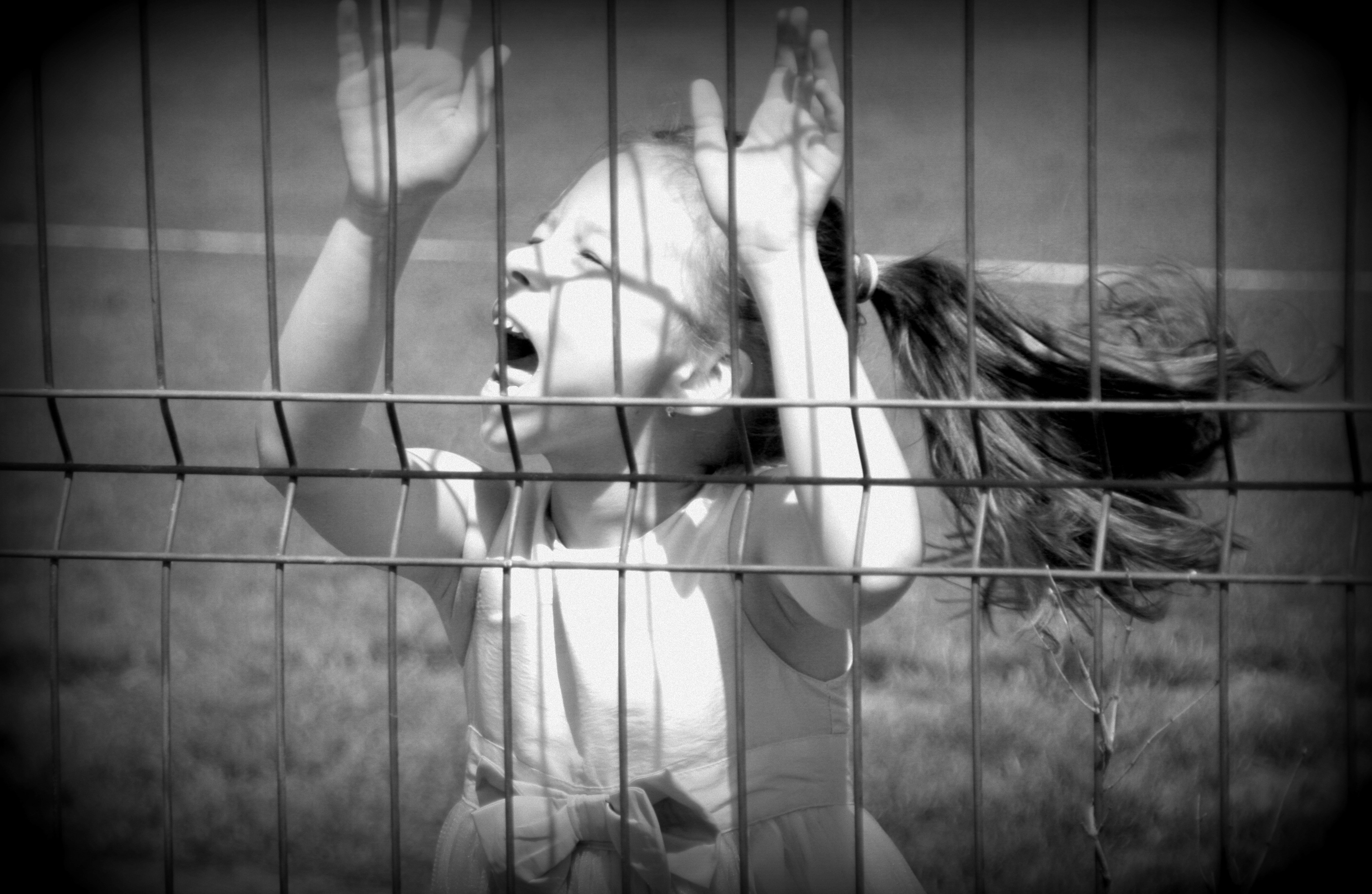 grayscale of girl near fence