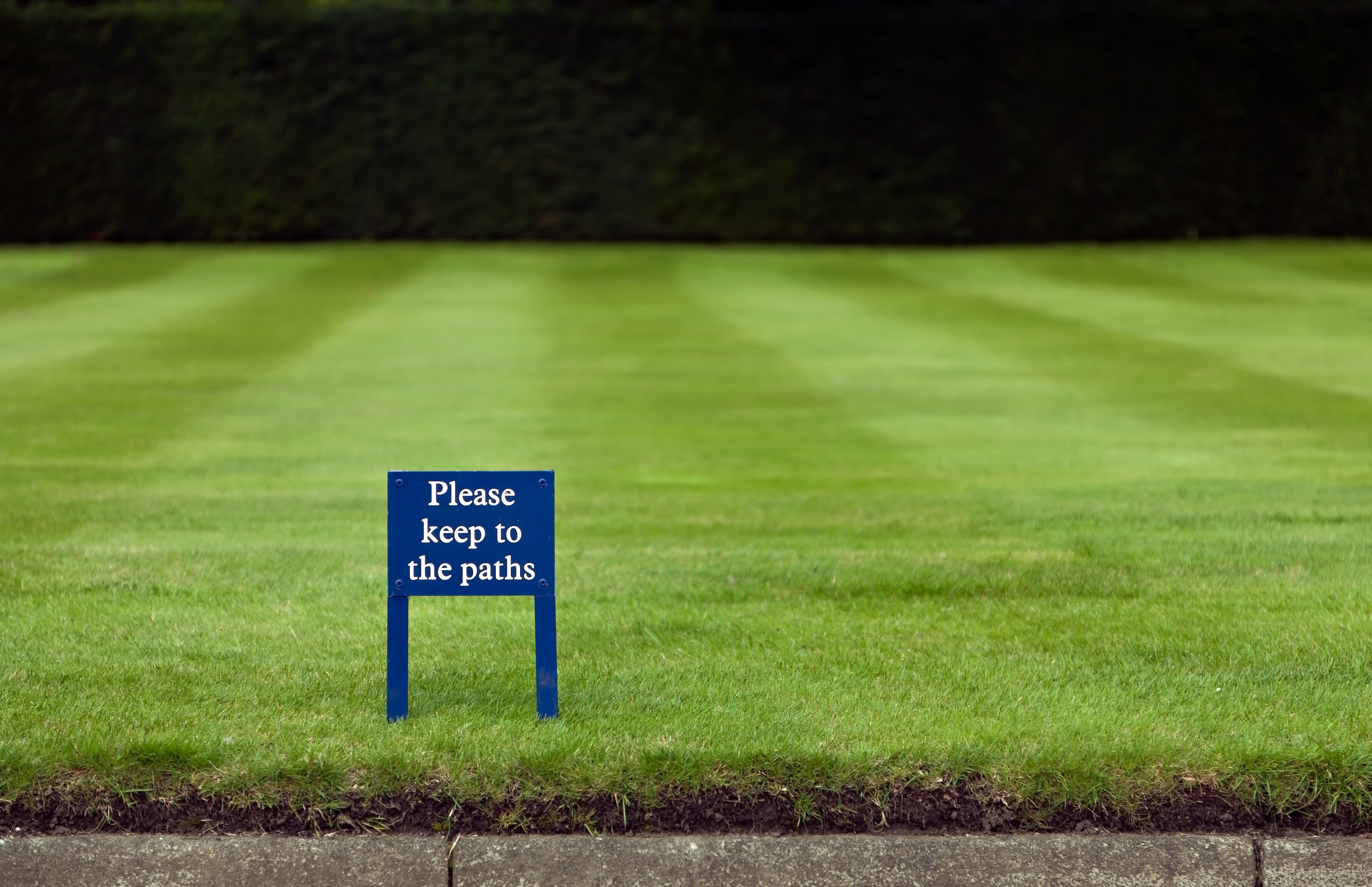 please keep to the paths signboard on grass field